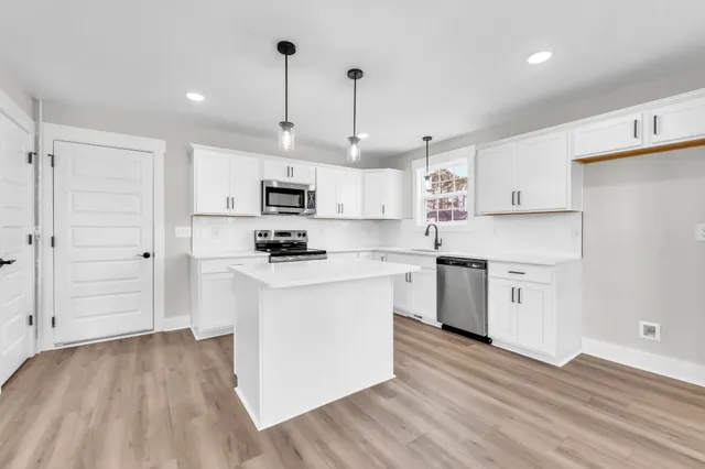 a kitchen with granite countertop a sink cabinets and stainless steel appliances