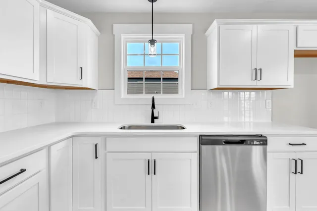 a kitchen with white cabinets and window