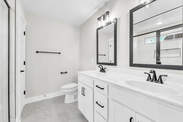 a bathroom with a toilet a sink a mirror and a shower