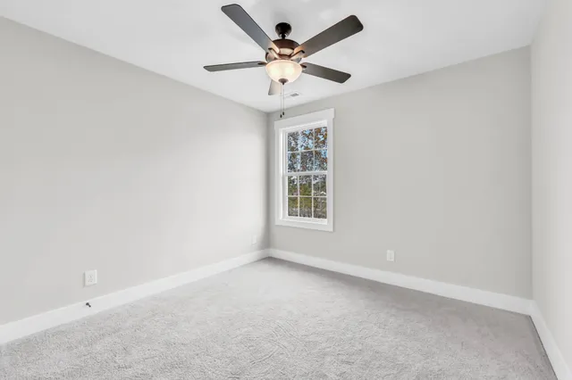 an empty room with windows and ceiling fan