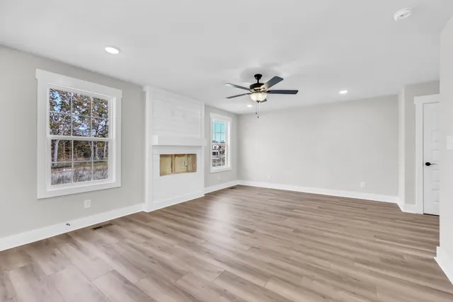 a view of an empty room with a window and wooden floor