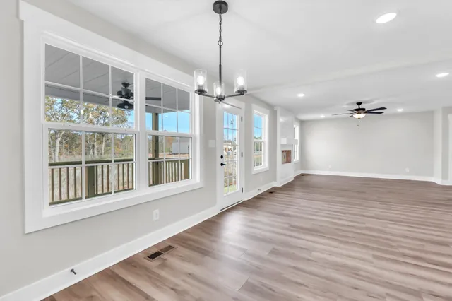 a view of an empty room with a window and wooden floor