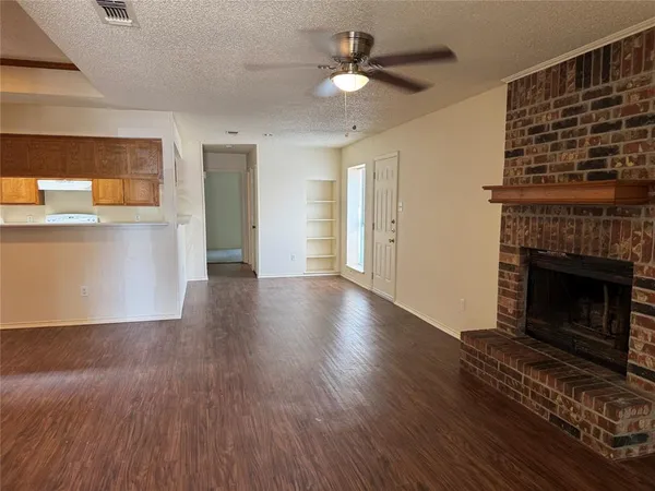 a view of a livingroom with wooden floor a ceiling fan and a window