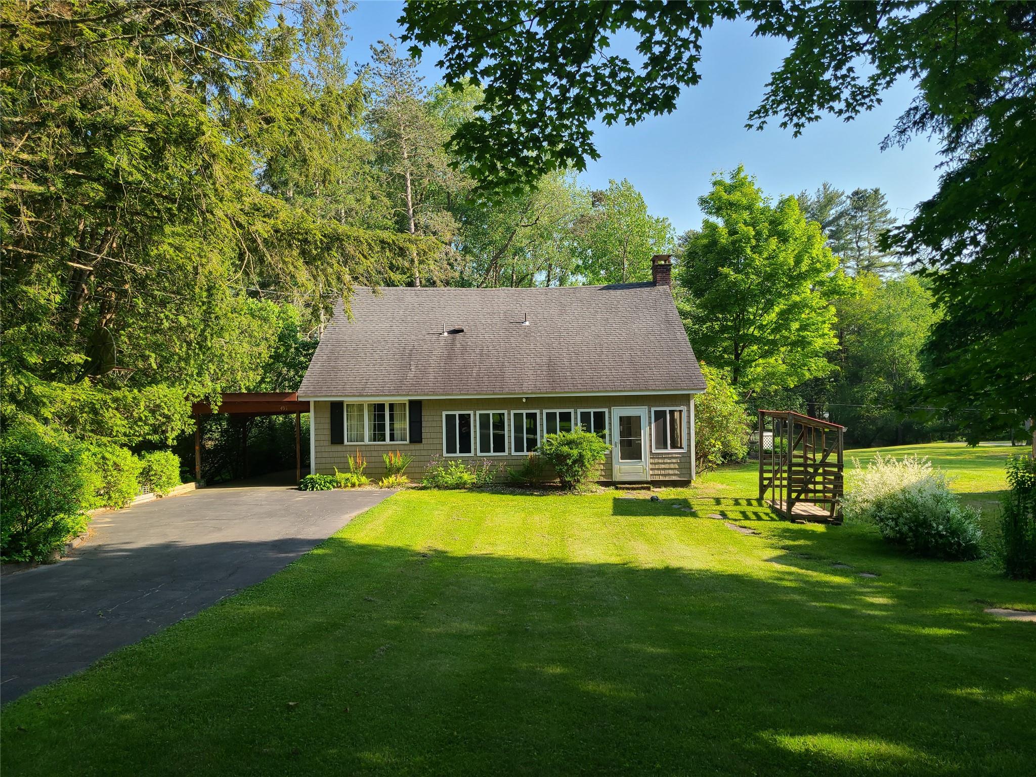 a view of a house with a big yard potted plants and large tree
