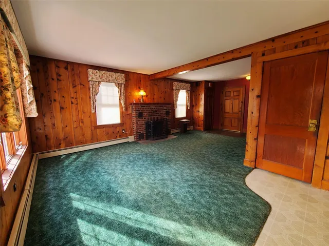 an empty room with windows and fireplace