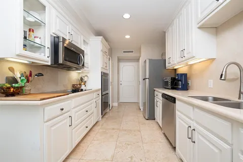 a kitchen with stainless steel appliances granite countertop white cabinets a sink a stove a refrigerator and a sink