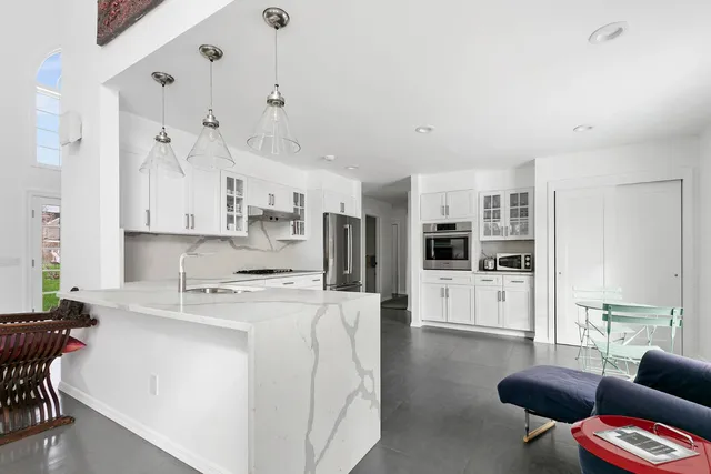 a kitchen with stainless steel appliances kitchen island granite countertop a stove top oven a sink a dining table and chairs with white cabinets