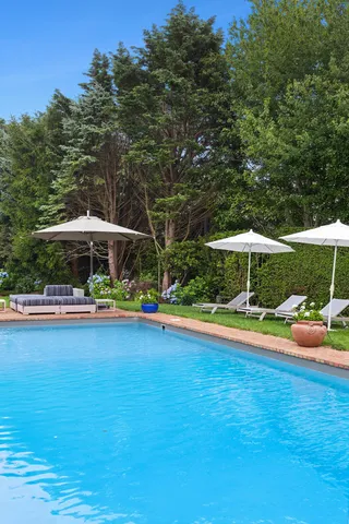 a view of a swimming pool with a table and chairs under an umbrella