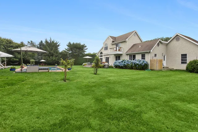 a view of a house with a big yard and large trees