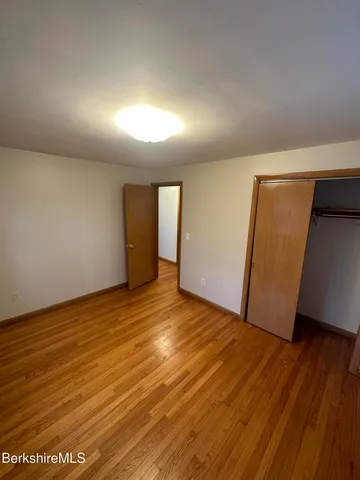 a view of an empty room with wooden floor and closet
