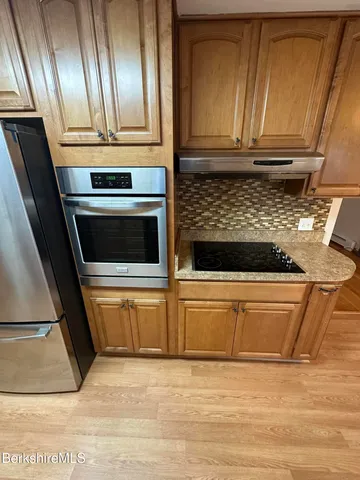 a kitchen with granite countertop a refrigerator and a stove top oven
