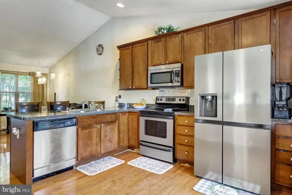 a kitchen with granite countertop stainless steel appliances a refrigerator a stove a microwave a sink and cabinets