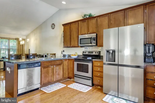 a kitchen with granite countertop stainless steel appliances a refrigerator a stove a microwave a sink and cabinets