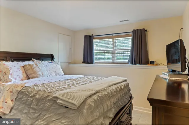 a bedroom with a bed and a flat tv screen on dresser