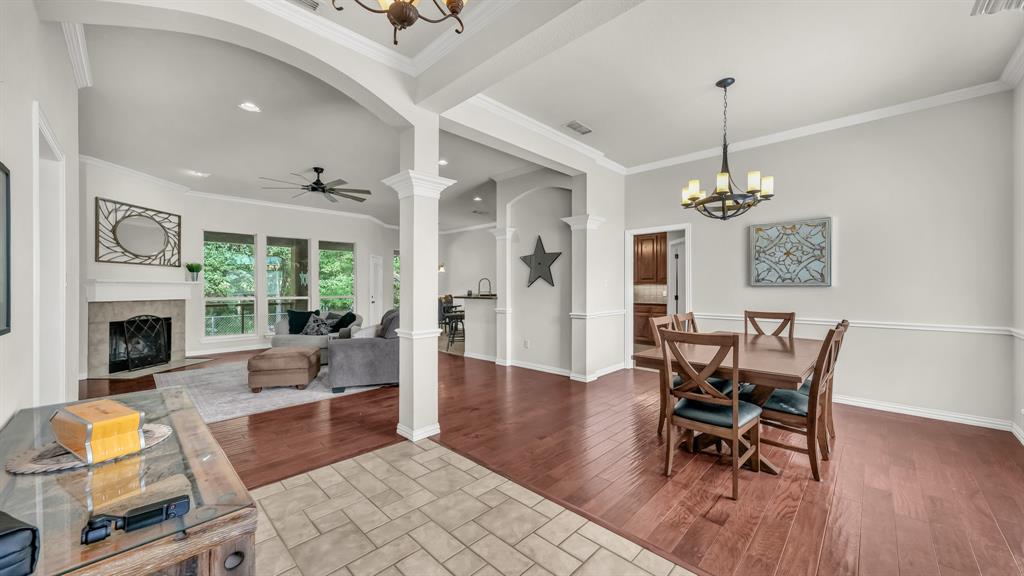 203 Mockingbird Lane Aledo, TX 76008 - Photo 7 of 37 Spacious interior showcasing wood-finish flooring, a formal dining area with chandelier lighting, and a living room with a fireplace, ceiling fan, and large windows