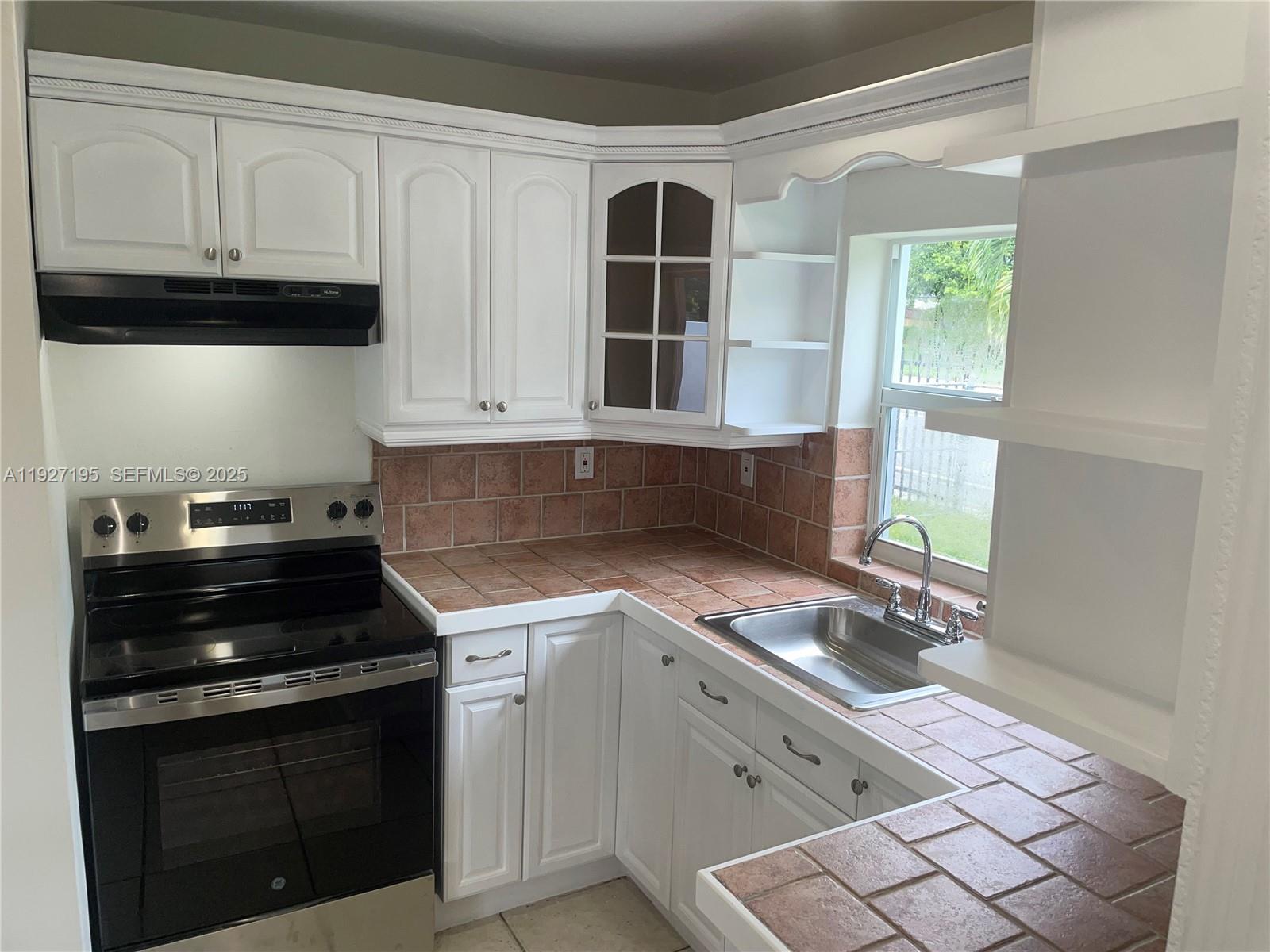 13017 Southwest 18th Terrace, Unit 13017 Miami, FL 33175 - Photo 11 of 21 a kitchen with granite countertop a stove sink and cabinets