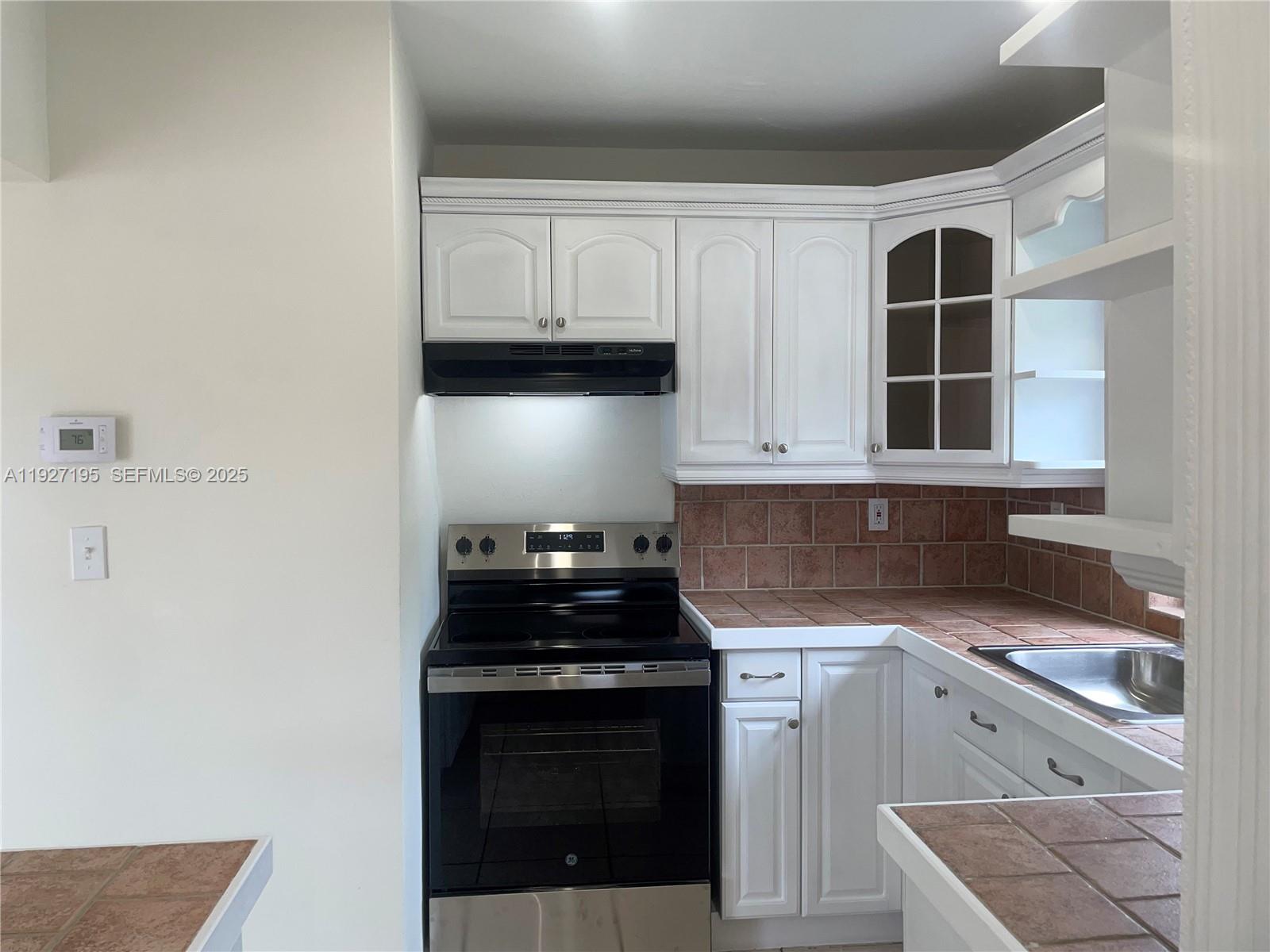 13017 Southwest 18th Terrace, Unit 13017 Miami, FL 33175 - Photo 3 of 21 a kitchen with granite countertop white cabinets and black appliances