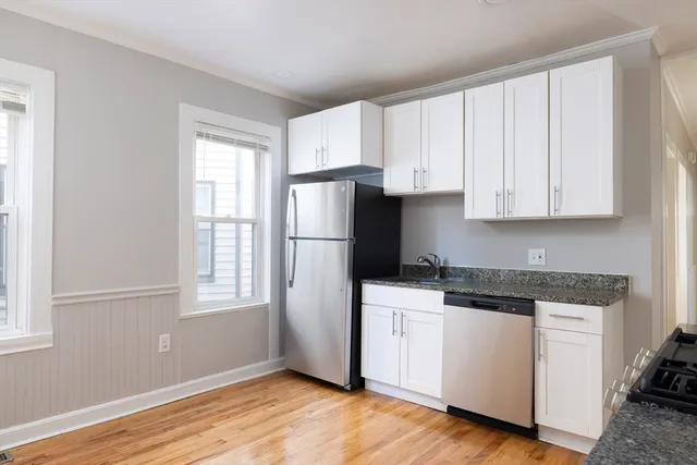 a kitchen with stainless steel appliances granite countertop white cabinets and window