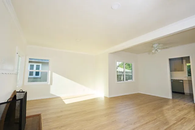 a view of an empty room with wooden floor and a window