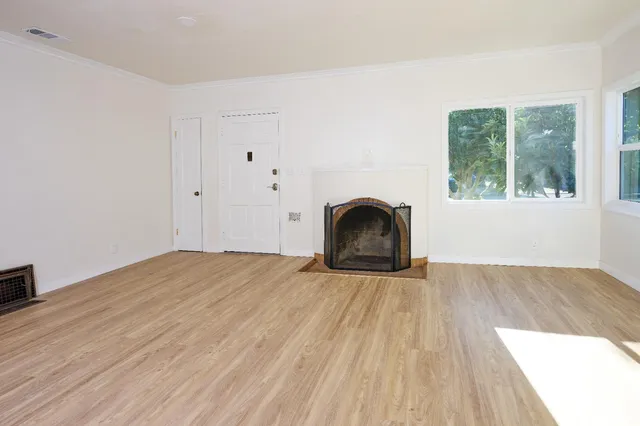a view of empty room with wooden floor and a fireplace