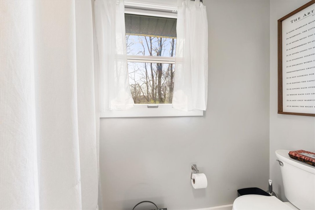 9555 Clyo Road Dayton, OH 45458 - Photo 18 of 31 This bright bathroom features a window offering views of mature trees, creating a serene atmosphere.