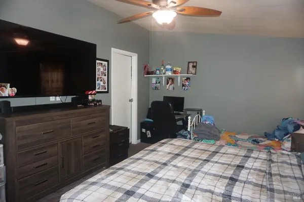 a bedroom with a bed and a flat tv screen on dresser