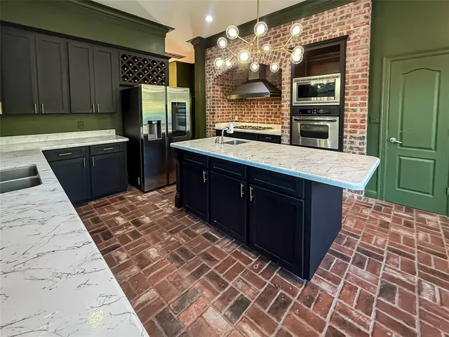 a kitchen with stainless steel appliances kitchen island granite countertop a refrigerator and a sink