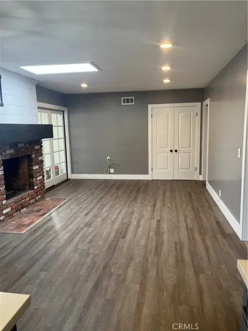 a view of a room with wooden floor and a kitchen
