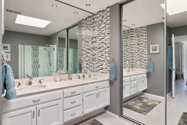 a bathroom with a double vanity sink mirror and shower