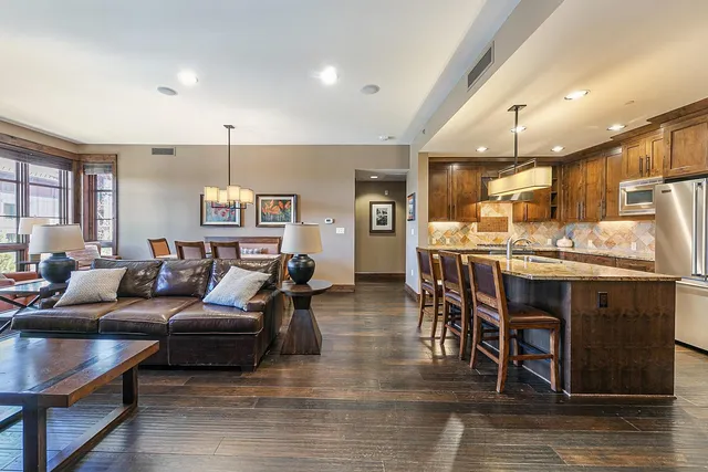 a living room with stainless steel appliances kitchen island granite countertop furniture and a wooden floor
