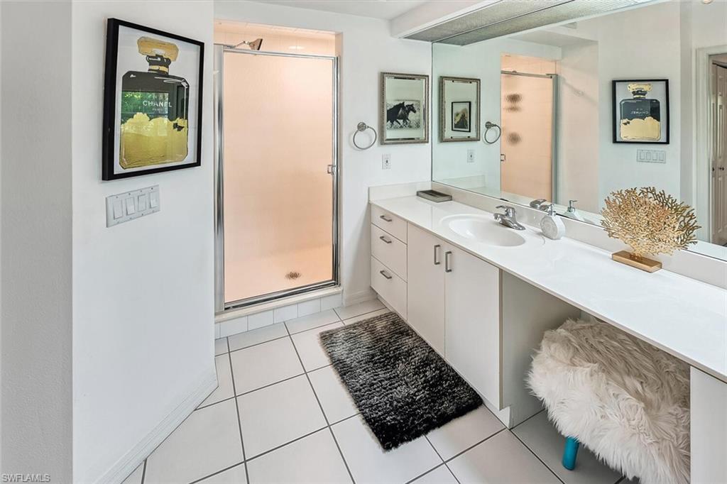 6910 Satinleaf Road North, Unit 101 Naples, FL 34109 - Photo 12 of 30 Bathroom featuring vanity, an enclosed shower, and tile patterned floors