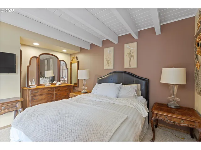 a bedroom with a large bed and a flat tv screen on dresser