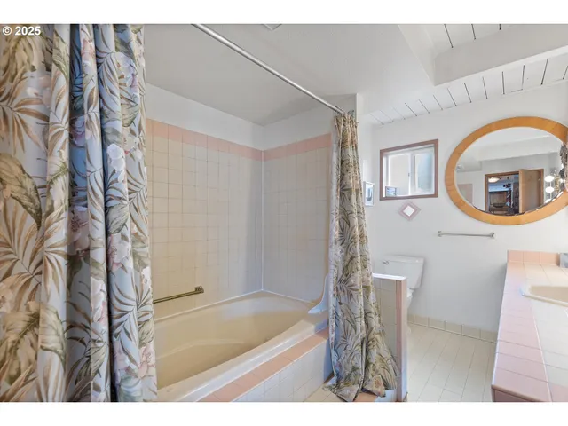 a bathroom with a tub a mirror and a shower