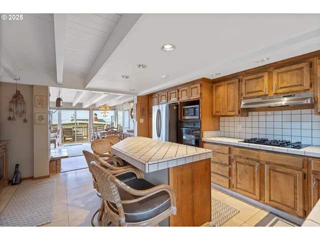 a open kitchen with stainless steel appliances wooden floor dining table and chairs
