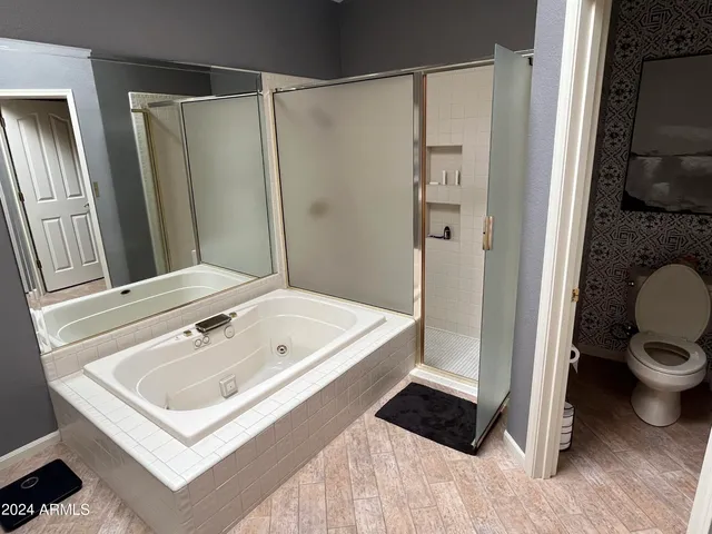 a kitchen with stainless steel appliances kitchen island granite countertop a table chairs in it and wooden floors