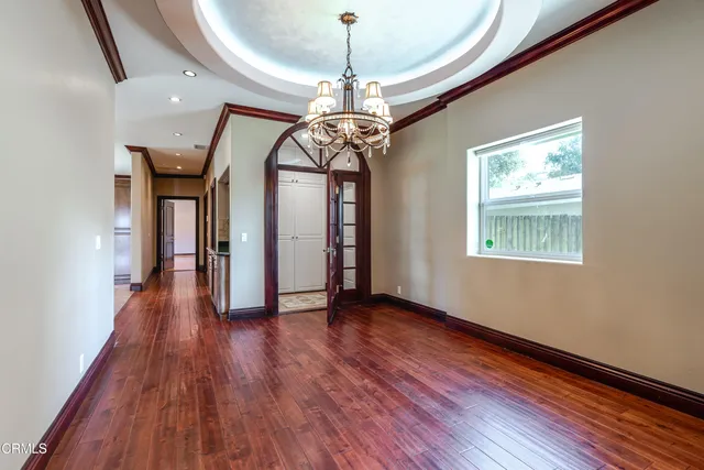 a view of a room with wooden floor chandelier and windows