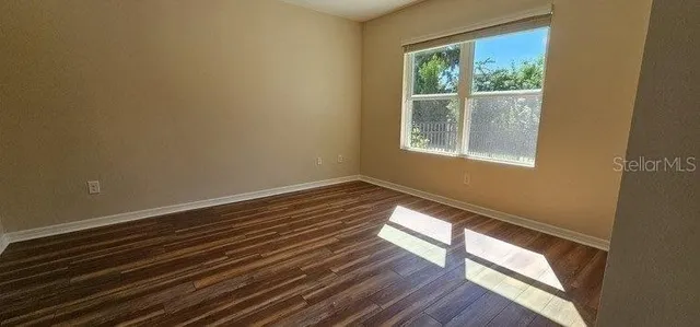 a view of an empty room with wooden floor and a window