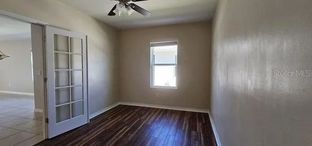 a view of empty room with wooden floor and fan