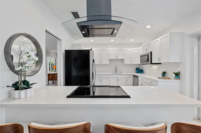 a living room with stainless steel appliances kitchen island a stove a refrigerator and a dining table with wooden floor