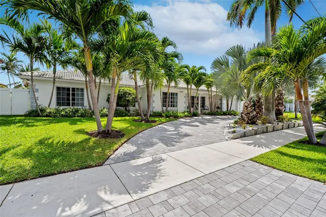 a view of a house with a yard and palm trees
