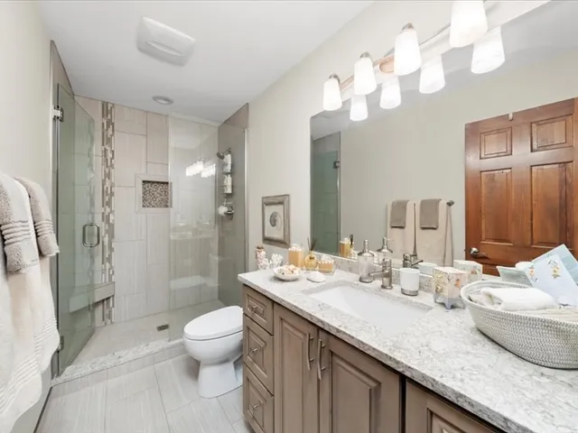 a bathroom with a granite countertop sink mirror and a shower