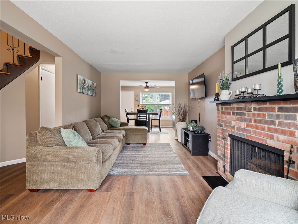 6488 State Road, Unit B5 Cleveland, OH 44134 - Photo 11 of 23 Living room featuring a brick fireplace, ceiling fan, and hardwood / wood-style floors