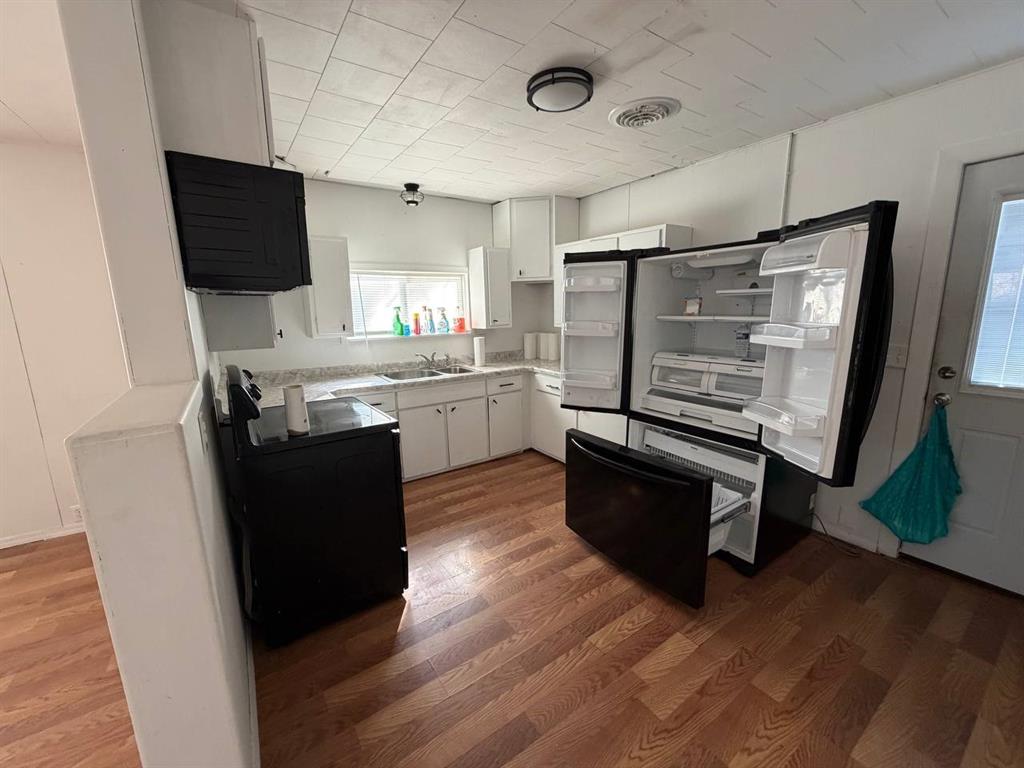 812 Tennessee Street Graham, TX 76450 - Photo 4 of 21 a kitchen with stainless steel appliances wooden floor and chairs