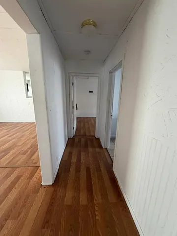 a view of a hallway with wooden floor and staircase