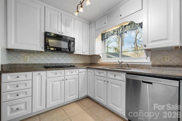 a kitchen with granite countertop white cabinets white appliances and a sink