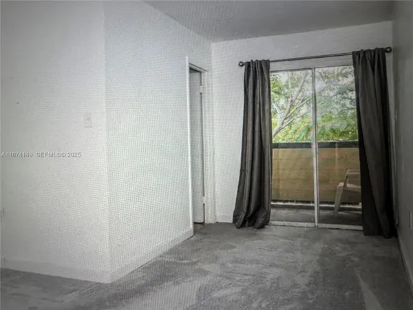 an empty room with sliding glass door and wooden floor