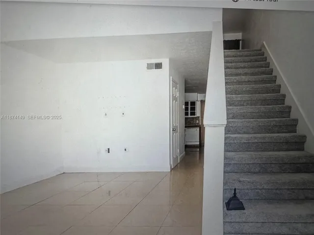 a view of an empty room with stairs and ventilation