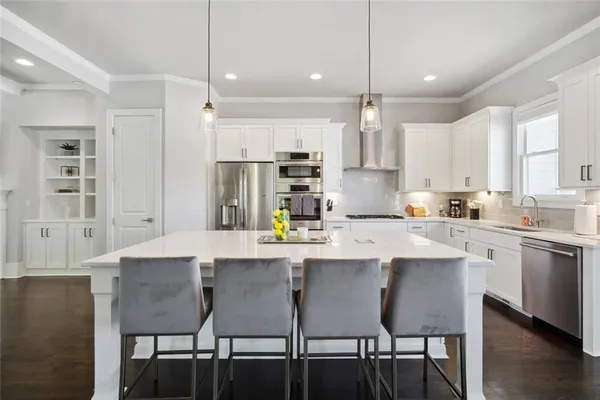 a kitchen with kitchen island a dining table chairs and white cabinets