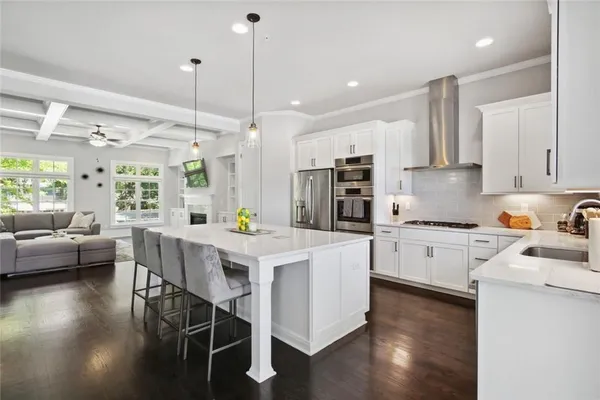 a kitchen with stainless steel appliances kitchen island granite countertop a stove a sink a refrigerator and white cabinets with wooden floor