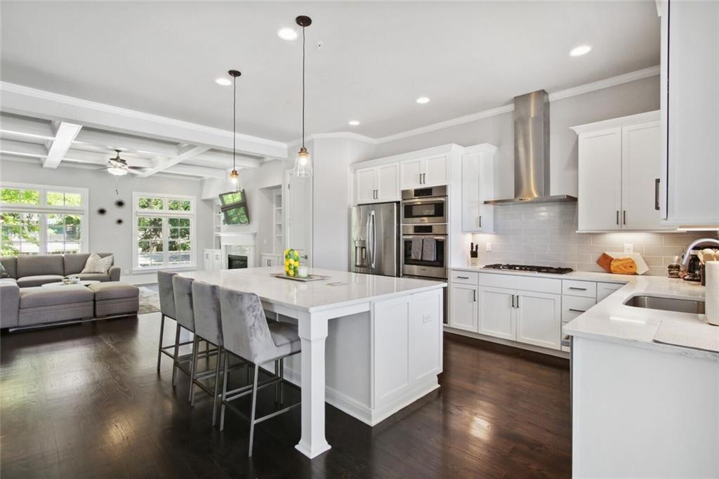 692 Drewry Street Northeast Atlanta, GA 30306 - Photo 10 of 25 a kitchen with stainless steel appliances kitchen island granite countertop a stove a sink a refrigerator and white cabinets with wooden floor